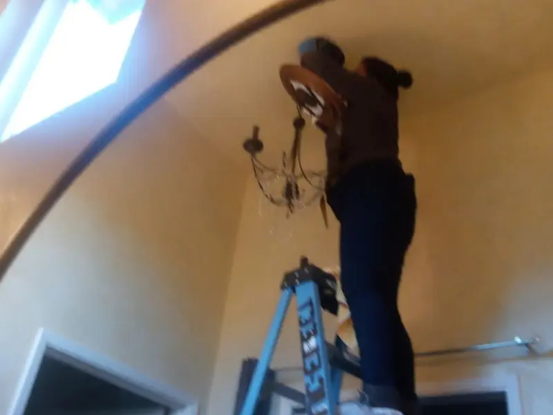 Electrician installing a chandelier in a San Joaquin residence